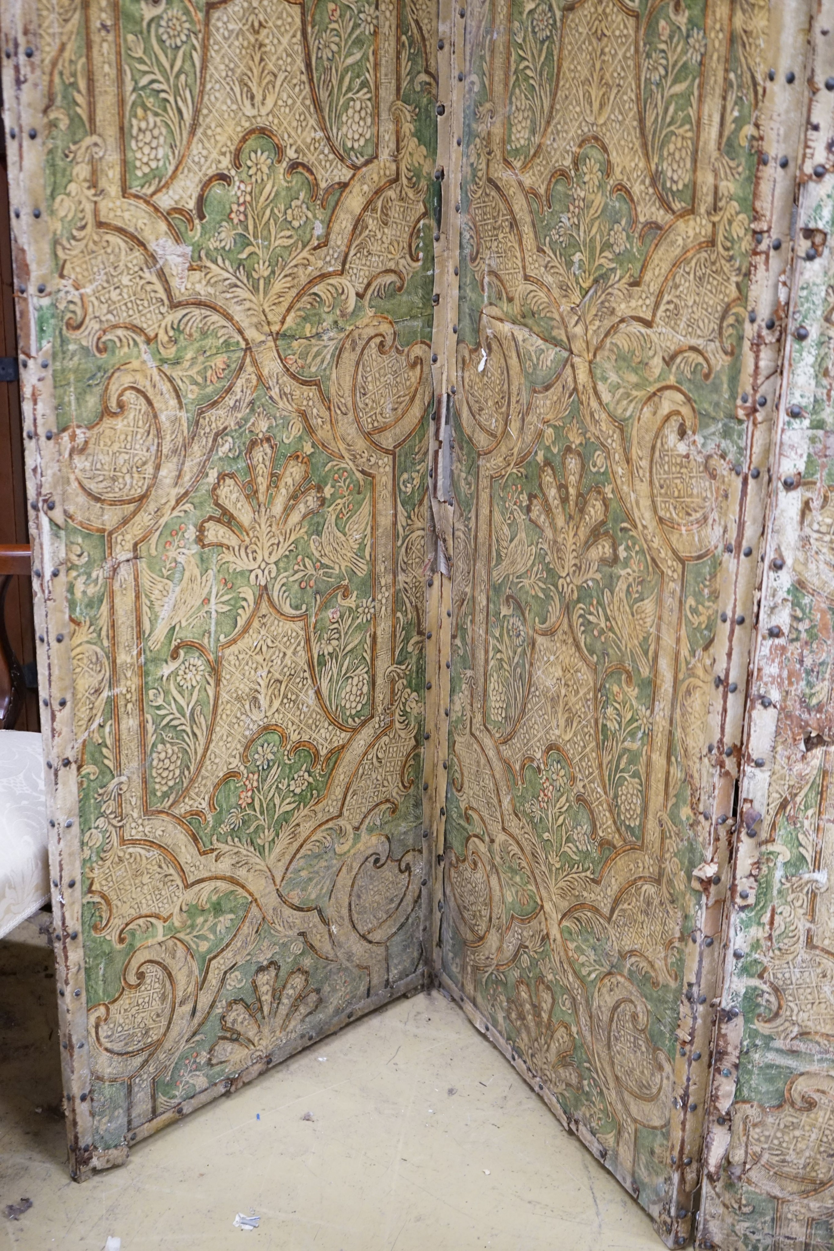A Spanish painted leather three fold dressing screen, each panel width 60cm, height 237cm